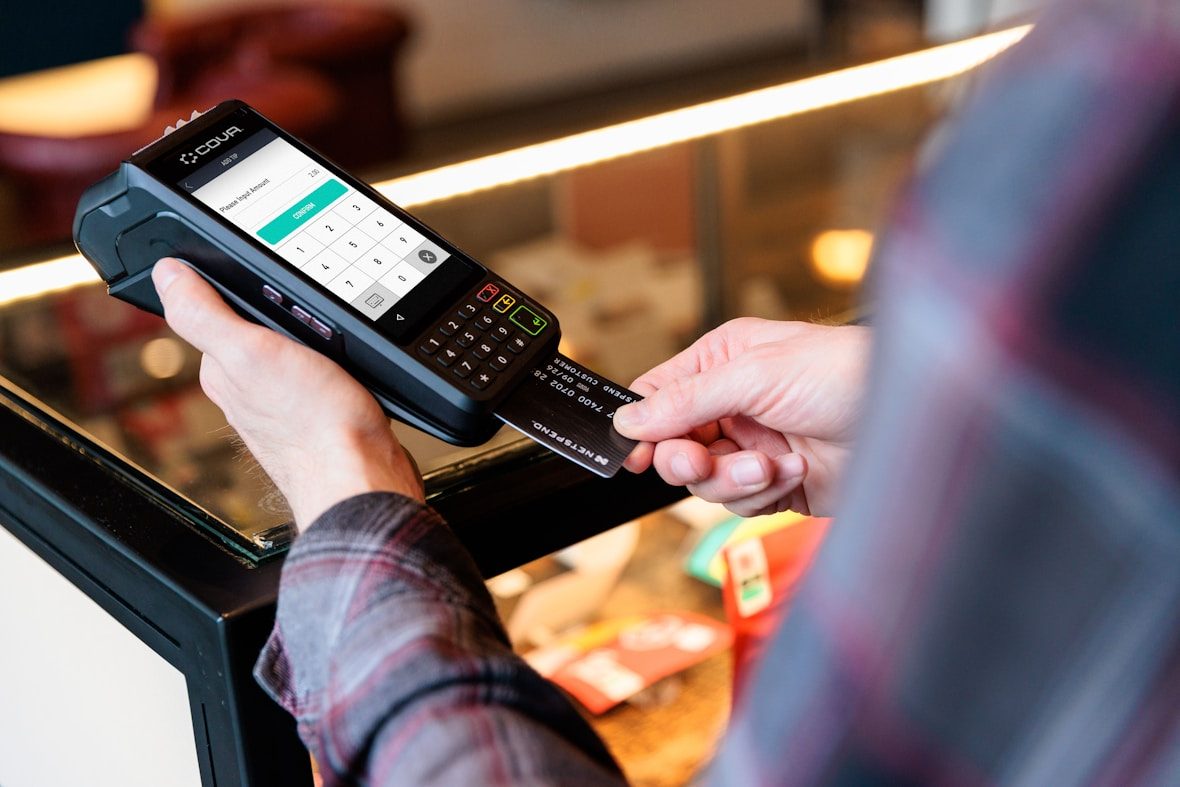 A customer pays at a handheld POS terminal with a tap card in a café